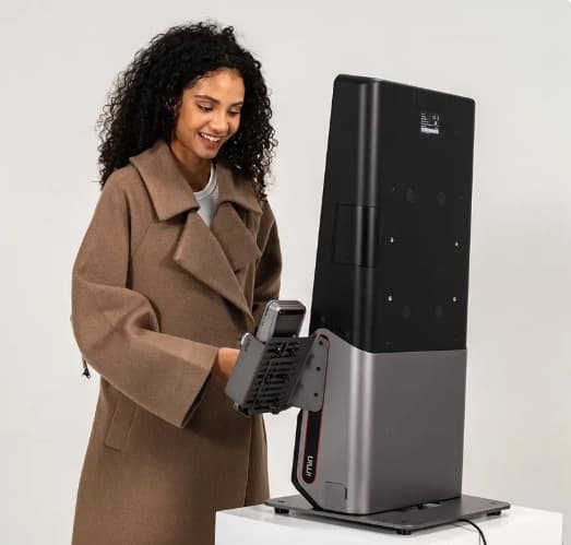 A woman using a Udok consultation kiosk with its handheld health-check device