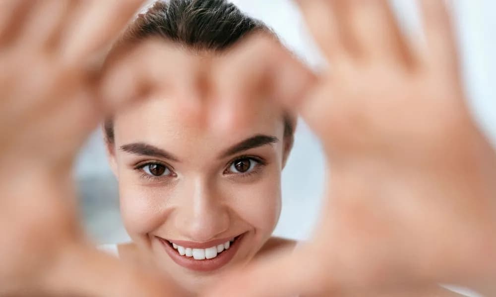 A smiling woman forming a heart shape with her hands