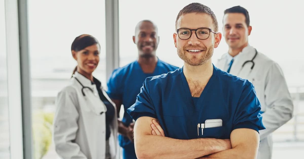 A team of four healthcare professionals in scrubs and white coats