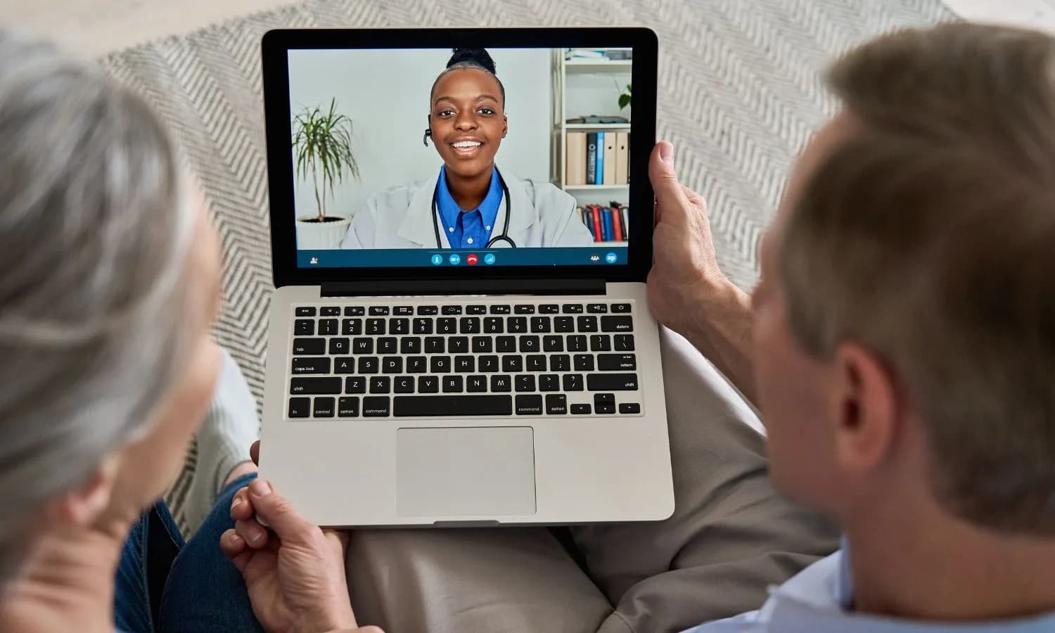 An older couple having a video consultation with a doctor on a laptop